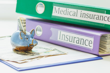 Insurance form, folders, piggy bank with American dollars, soft focus backgroundの写真素材