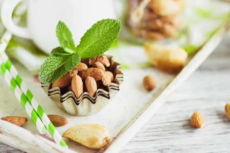 Mint leaves, almonds and jar with milk on the wooden tray, soft focus backgroundの写真素材