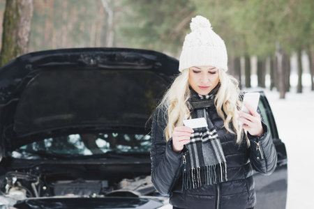 Young woman calls by phone in car service, winter time