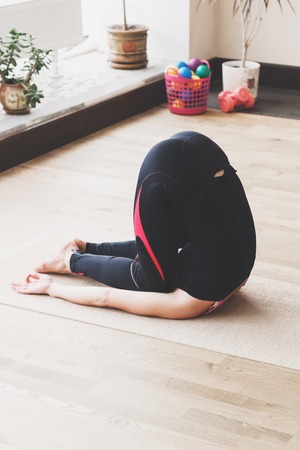 Beautiful woman makes the yoga exercise on the mat, indoors, soft focus backgroundの写真素材