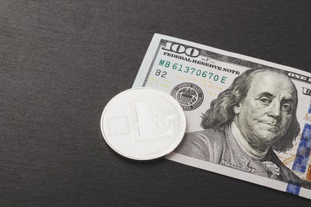 Litecoin and hundred dollars on the black slate stone, soft focus backgroundの写真素材