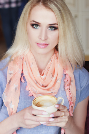 Portrait of beautiful woman in the cafe with a cup of cappuccino, soft focus backgroundの写真素材