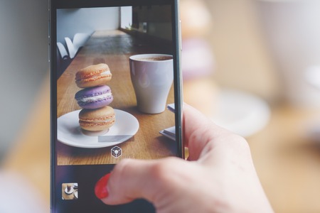 French colored macarons on the plate and a cup of coffee, soft focus backgroundの写真素材