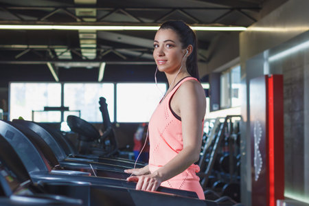 Sporty young woman makes sport exercises in the gym, soft focus background