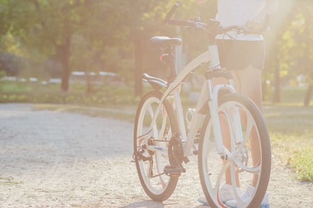 Young sporty woman with a bike on a sunset, soft focus backgroundの写真素材