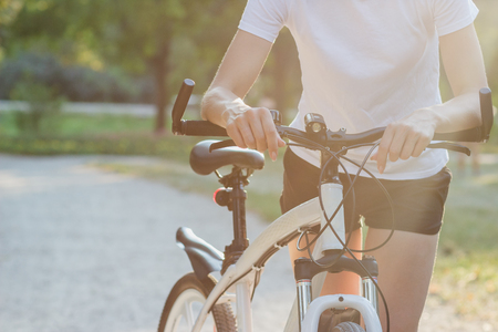 Young sporty woman with a bike on a sunset, soft focus backgroundの写真素材