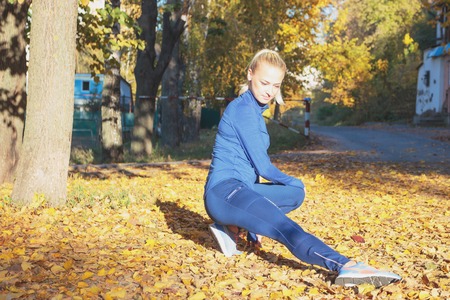 Beautiful sporty woman does sport exersices in the park, autumn time, soft focus backgroundの写真素材