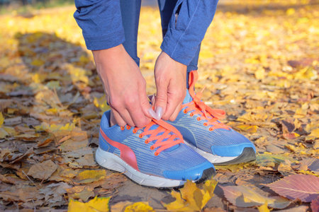 Sportswoman in the blue sneakers and sport clothes, outdoors, soft focus background
