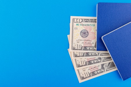 Two blue passports and American dollars on the light blue base, top viewの写真素材