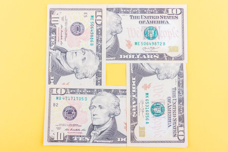 Different American dollars on the light yellow base, top view