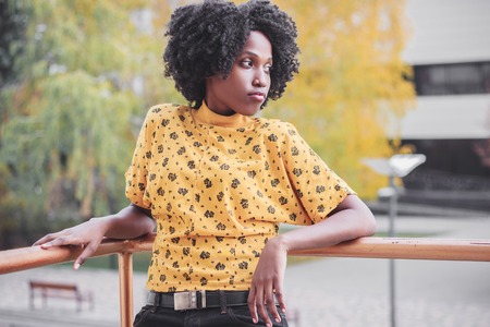 Young smiling dark-skinned woman dressed in casual clothes, blurred backgroundの写真素材