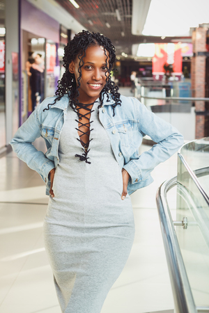 Young dark-skinned woman dressed in casual clothes in the mall, blurred backgroundの写真素材