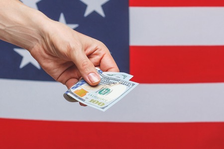 Hand with American dollars on the national flag backgroundの写真素材