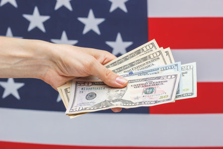 Hand with American dollars on the national flag background