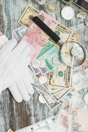 Hands in white gloves, different American dollars and Indonesian rupiahs, numismatics concept, blurred backgroundの写真素材