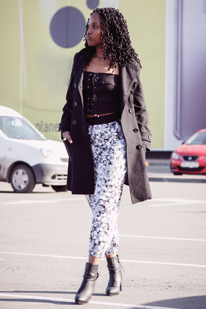 Young dark-skinned woman dressed in fashion clothes walking on the street, blurred backgroundの写真素材