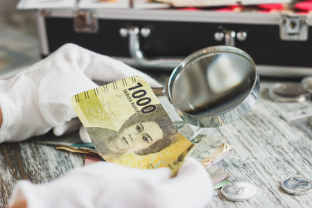 Indonesia: Hands in the white gloves hold different banknotes, top viewの写真素材