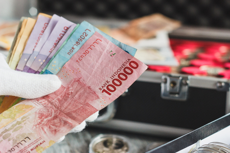 Indonesia: Hands in the white gloves hold different banknotes, top viewの写真素材