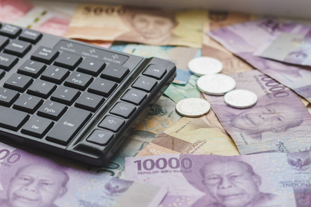 Concept: Different types of Indonesia money and keyboard, top viewの写真素材
