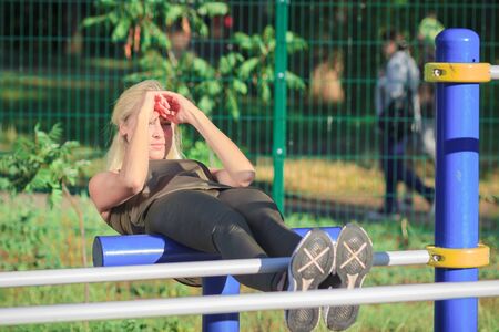 Beautiful woman in sneakers and sport clothes makes sport exercises on the athletic field, soft focus backgroundの写真素材