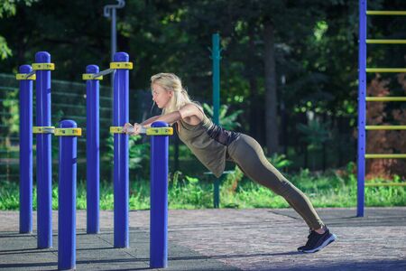 Beautiful young woman makes sport exercises on the sport ground, blurred backgroundの写真素材