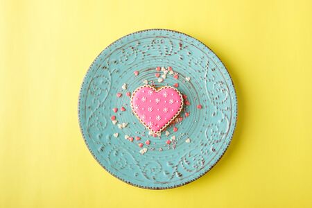 Pink cookie heart shaped with different patterns on the light yellow backgroundの写真素材
