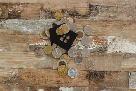 Gold, silver coins and decorative house, wooden backgroundの写真素材