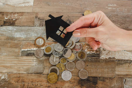 Gold, silver coins and decorative house, wooden backgroundの写真素材