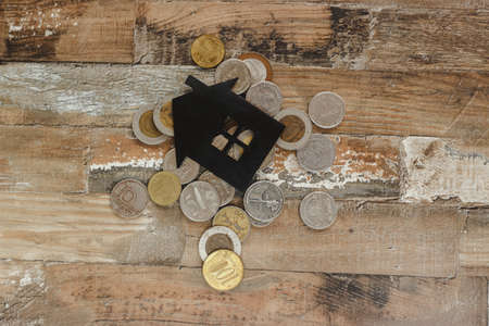 Gold, silver coins and decorative house, wooden backgroundの写真素材