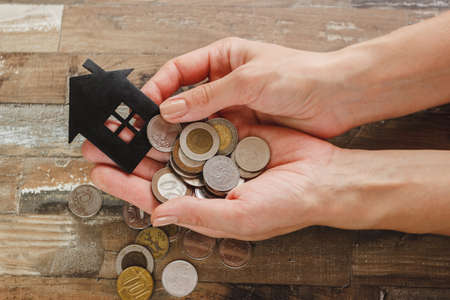 Gold, silver coins and decorative house, wooden backgroundの写真素材