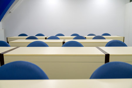 Interior of a lecture hall with rows of chairs and tables.の写真素材