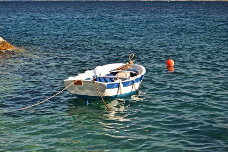 Tiny wooden boat on an azure seaの写真素材