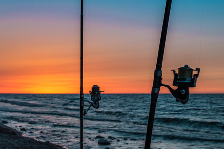 Sunset behind fishing rods in a seaの写真素材