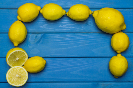 Whole and cut lemons on blue wooden surfaceの写真素材