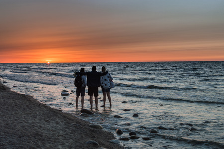 Group of people enjoying sunset at sea shoreの写真素材