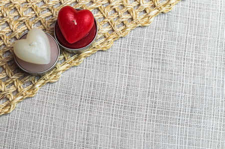 Red and white heart candles on white material and straw mat backgroundの写真素材