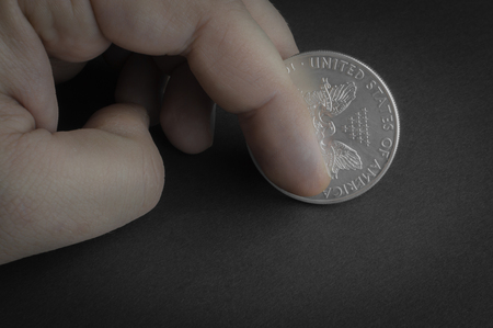 Silver one dollar coin standing on black surface - business concept, isolated.の写真素材