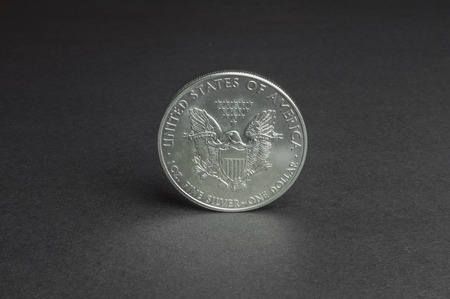 Silver one dollar coin standing on black surface - business concept, isolated.の写真素材