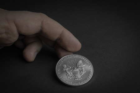 Silver one dollar coin standing on black surface - business concept, isolated.の写真素材