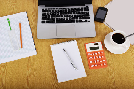 Mock up objects such as computer, calculator and smartphone on a wooden background, front viewの写真素材