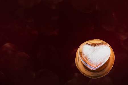 Heart shape ice on mini baked clay vase and dark red backgroundの写真素材