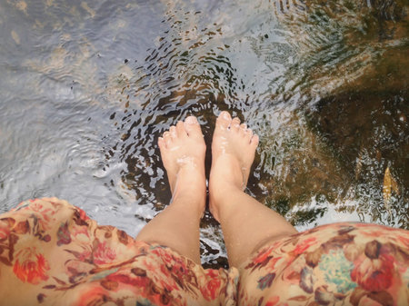 Top view of women leg and feet dip in crystalline stream, summer relaxing feelingの写真素材