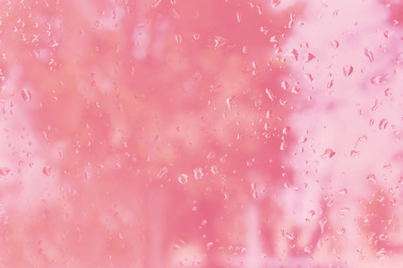 Abstract blurred background with rain drop on glass mirror in sweet pastel pink colourの写真素材