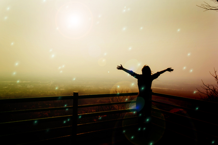 Silhouette back of women raising two arm embracing to sunlight and world in freedom conceptの写真素材