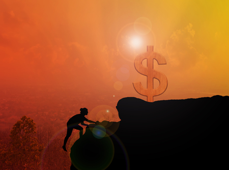 Women silhouette climbing on cliff to dollar symbol with blurred city topview with sunlight effect, money freedom, climbing to dollar conceptの写真素材