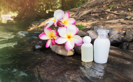Mini set of bubble bath shower gel liquid with flowers and pebble on waterfall rock  with natural water relaxing feeling background and copy sapceの写真素材