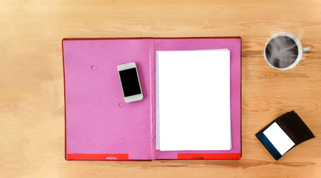 Blank paper note on file folder and mobile phone on wood table with cup of hot black coffee and...