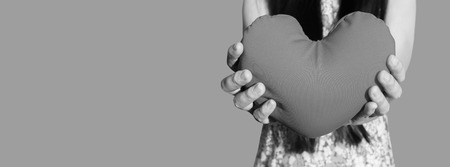 Isolated hands gently raise and hold red heart with valentine love and respect on blank area red background, women and healthy heart care with clipping pathの写真素材
