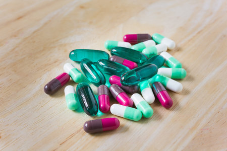 Colourful medicine capsules group on wooden plate