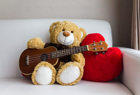 Lovely brown bear gift doll playing ukulele an red hearts on sofaの写真素材